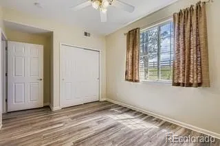 a view of empty room with wooden floor and fan