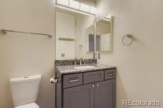 a bathroom with a granite countertop sink a toilet and a mirror