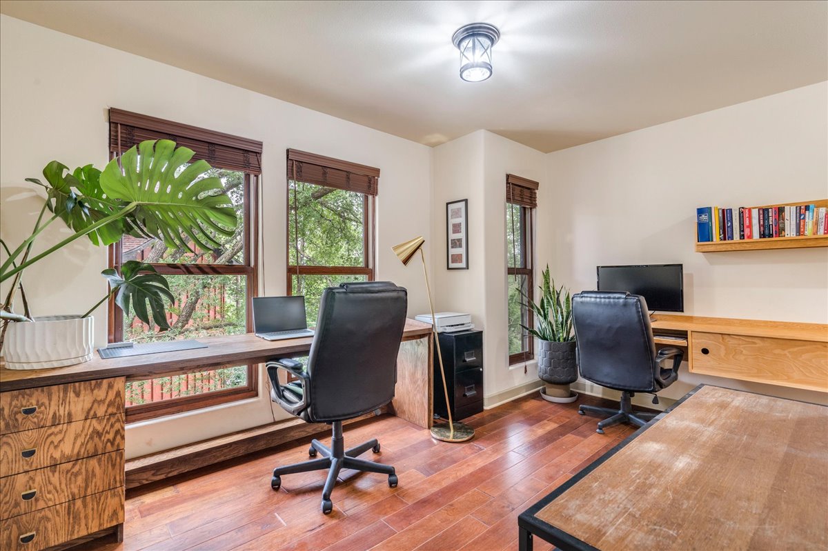 3012 South 4th Street, Unit B Austin, TX 78704 - Photo 22 of 40 Room featuring wood-finish flooring, multiple windows with wooden blinds, a built-in wooden desk, and a wall-mounted wooden shelf
