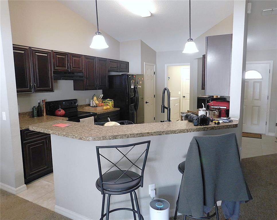 17477 Southwest 36th Terrace Ocala, FL 34473 - Photo 13 of 47 a kitchen with stainless steel appliances granite countertop a refrigerator a stove a sink dishwasher a dining table and chairs with wooden floor