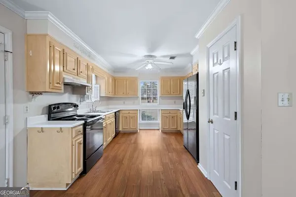 a kitchen with stainless steel appliances granite countertop a stove top oven a refrigerator a sink and dishwasher with wooden floor