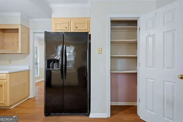 a view of a refrigerator in kitchen and an empty room with wooden floor windows