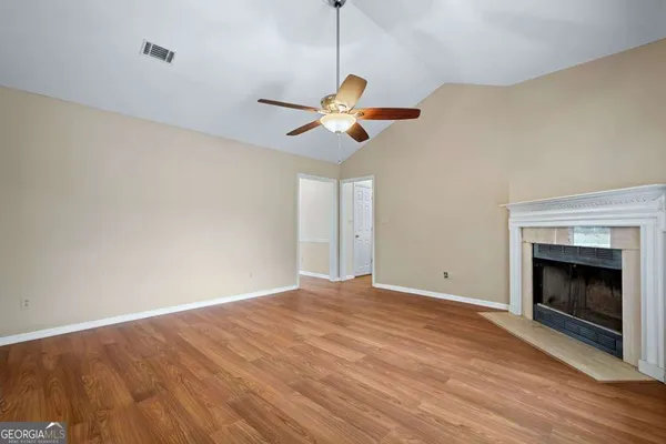 a view of an empty room with chandelier fan and wooden floor