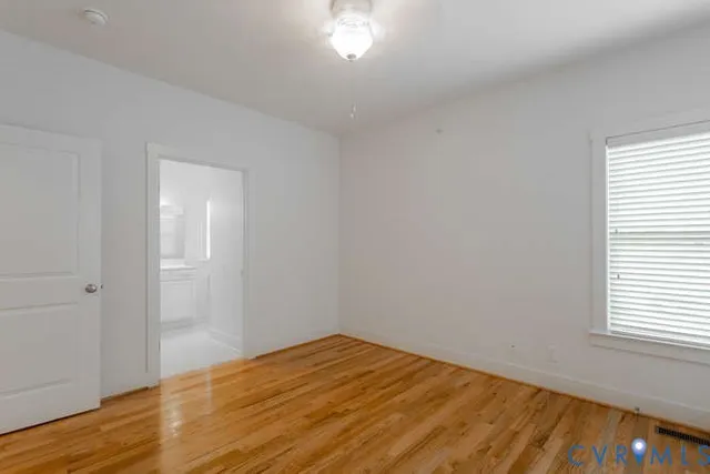 a view of empty room with wooden floor and fan