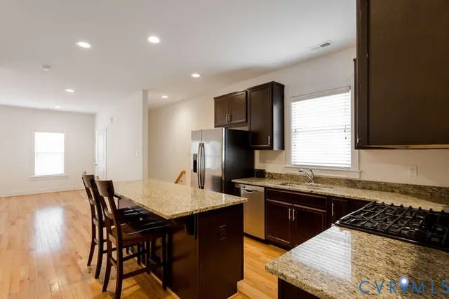 a kitchen with stainless steel appliances granite countertop a sink a stove a dining table and chairs