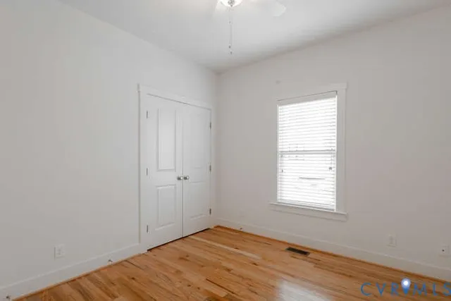 a view of an empty room with wooden floor and a window