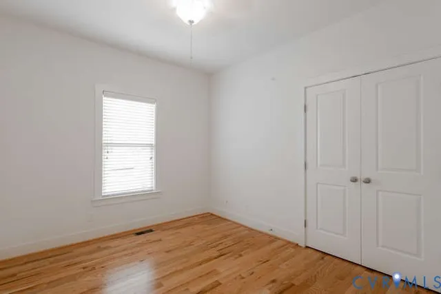 an empty room with wooden floor and windows
