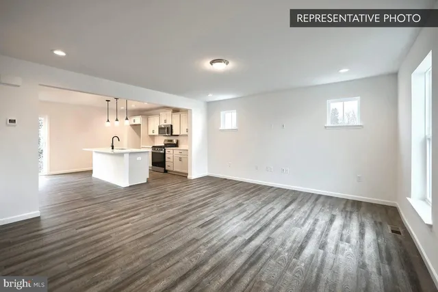 a big room with wooden floor and kitchen view