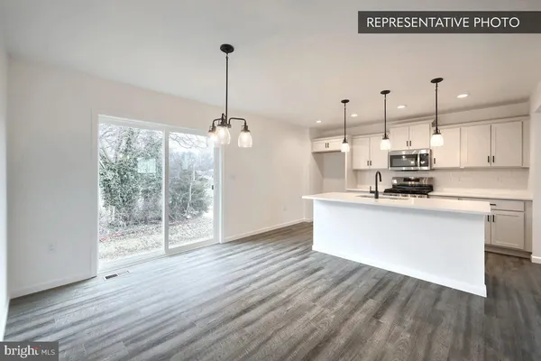 a kitchen with stainless steel appliances granite countertop a refrigerator a oven a white counter space and wooden floor