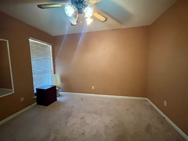 en empty room with windows and chandelier fan