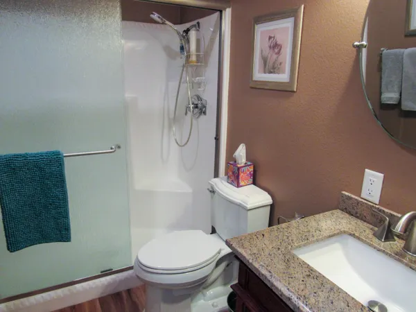 a bathroom with a granite countertop sink toilet and shower