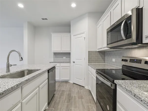 a kitchen with stainless steel appliances granite countertop a sink dishwasher stove and microwave with wooden cabinets