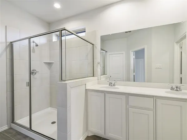 a bathroom with a double vanity sink mirror and shower
