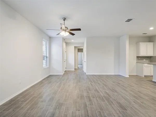 a view of empty room with wooden floor and ceiling fan