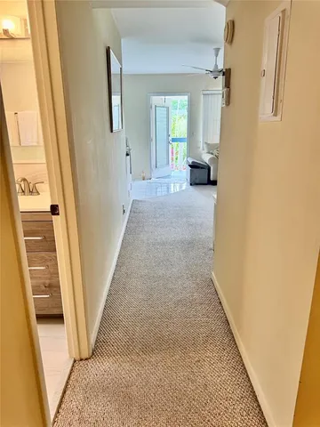 a view of a hallway to a livingroom with wooden floor and stairs