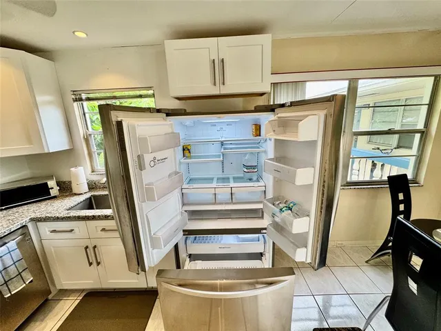 a kitchen with granite countertop white cabinets and white appliances