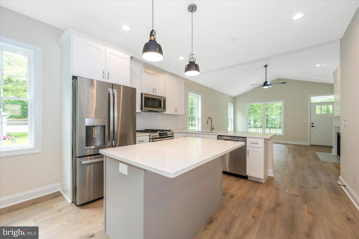 216 Brooks Lane St. Michaels, MD 21663 - Photo 14 of 37 a open kitchen with stainless steel appliances granite countertop a refrigerator a sink dishwasher a stove and white countertops with wooden floor