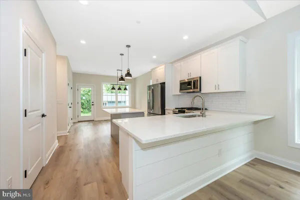a view of a kitchen with a sink and dishwasher with wooden floor
