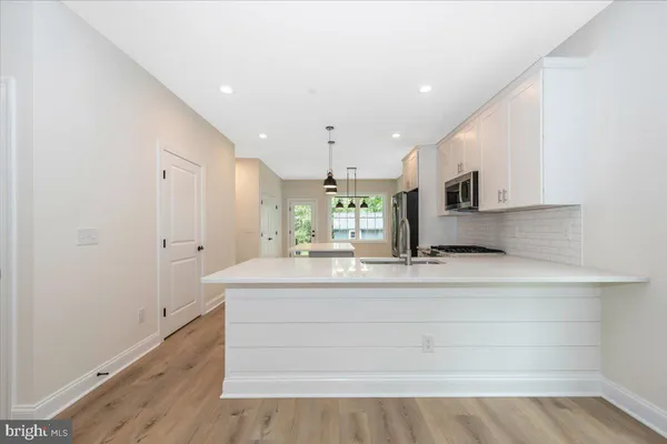 a large white kitchen has a large island oven a sink and white cabinets