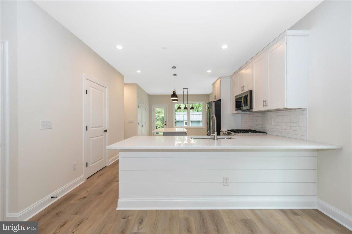216 Brooks Lane St. Michaels, MD 21663 - Photo 17 of 37 a large white kitchen has a large island oven a sink and white cabinets
