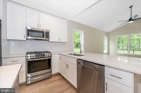 a kitchen with stainless steel appliances granite countertop a sink a stove a microwave and wooden cabinets