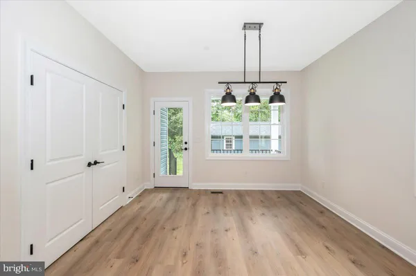 a view of an empty room with window and hardwood floor