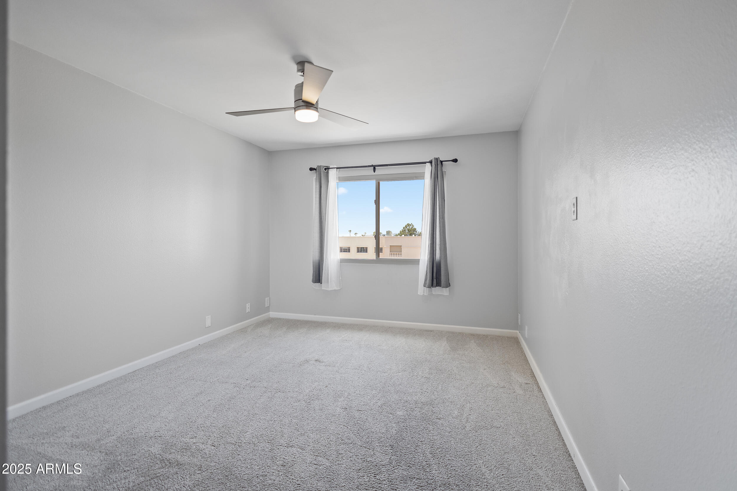 7920 East Camelback Road, Unit 601 Scottsdale, AZ 85251 - Photo 13 of 35 an empty room with a window and chandelier fan