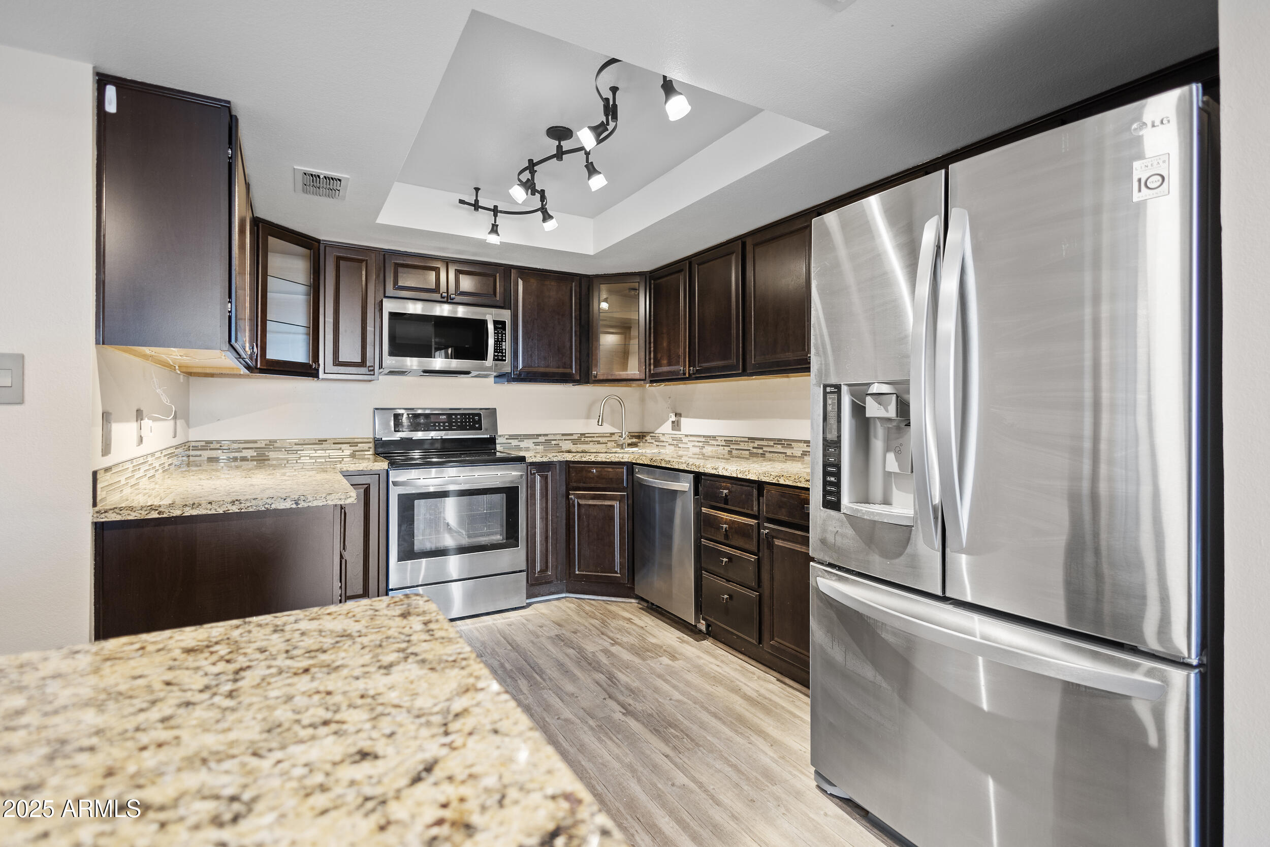 7920 East Camelback Road, Unit 601 Scottsdale, AZ 85251 - Photo 2 of 31 a kitchen with kitchen island granite countertop stainless steel appliances and a refrigerator