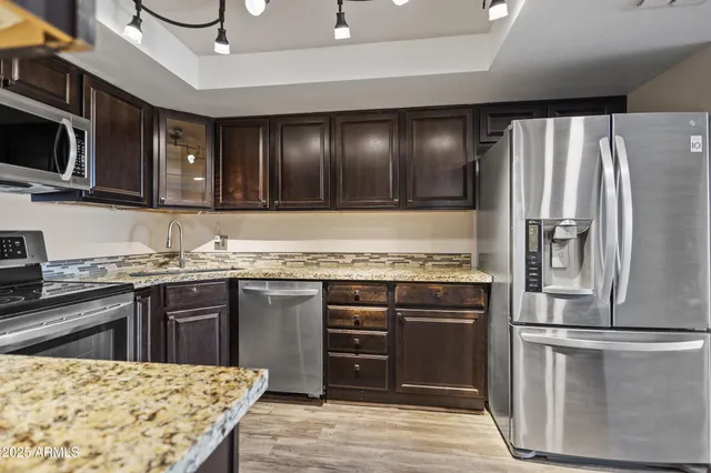 a kitchen with stainless steel appliances granite countertop a stove top oven a sink and a refrigerator