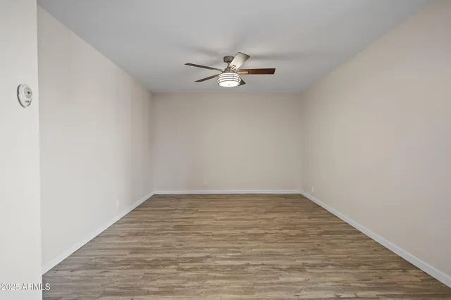 an empty room with a window and ceiling fan
