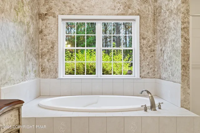 a white bath tub sitting in a bathroom next to a window
