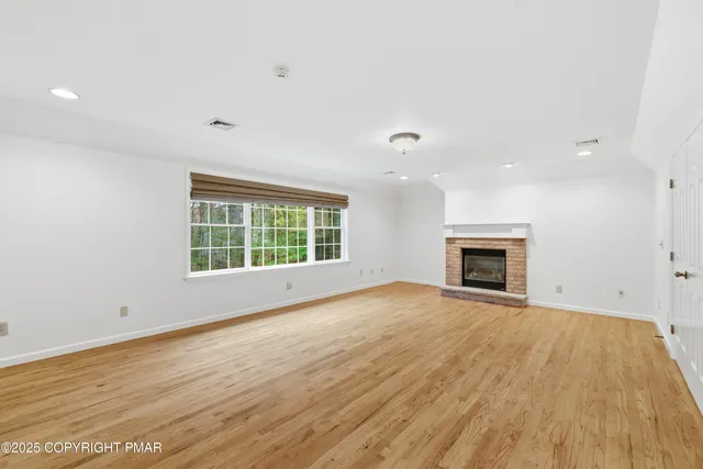 a view of empty room with wooden floor and fireplace