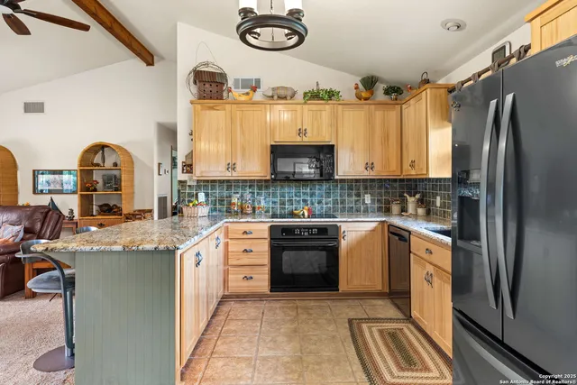 a kitchen with stainless steel appliances granite countertop a refrigerator a stove a sink and a microwave