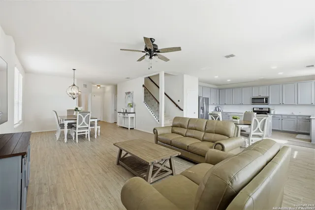 a living room with furniture kitchen view and a wooden floor