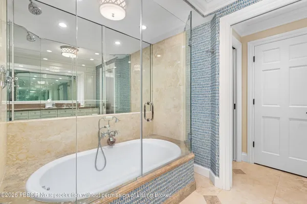 a bathroom with a tub a mirror and a shower