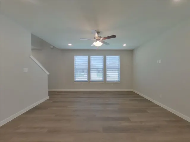 an empty room with chandelier fan and windows