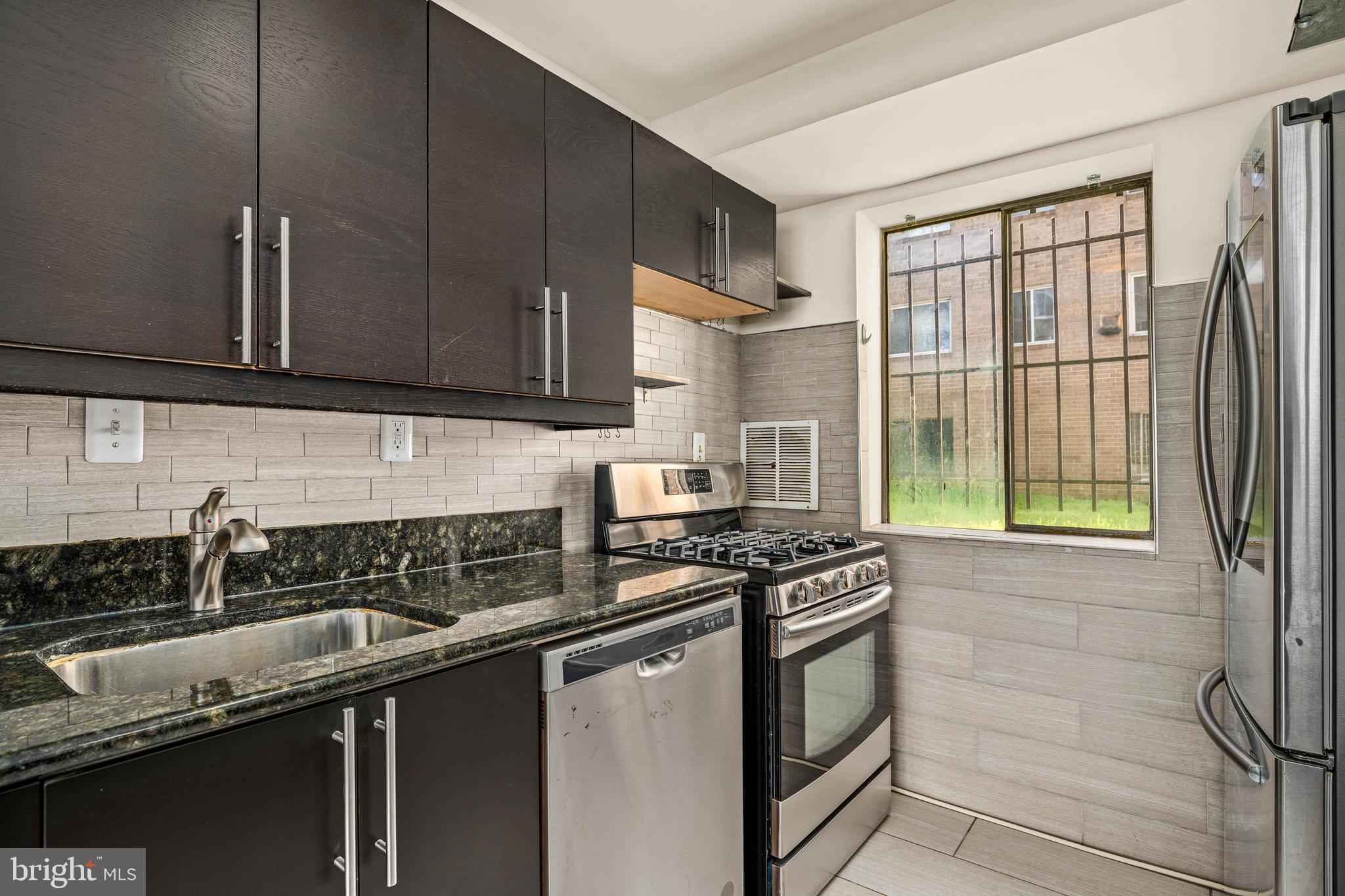 1920 Naylor Road Southeast, Unit T2 Washington, DC 20020 - Photo 12 of 25 a kitchen with granite countertop a sink a stove and cabinets