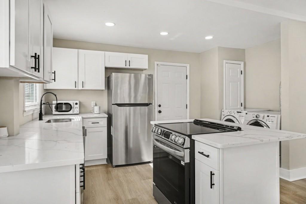 1515 Jonesboro Road Southeast Atlanta, GA 30315 - Photo 19 of 32 a kitchen that has a refrigerator a stove and white cabinets