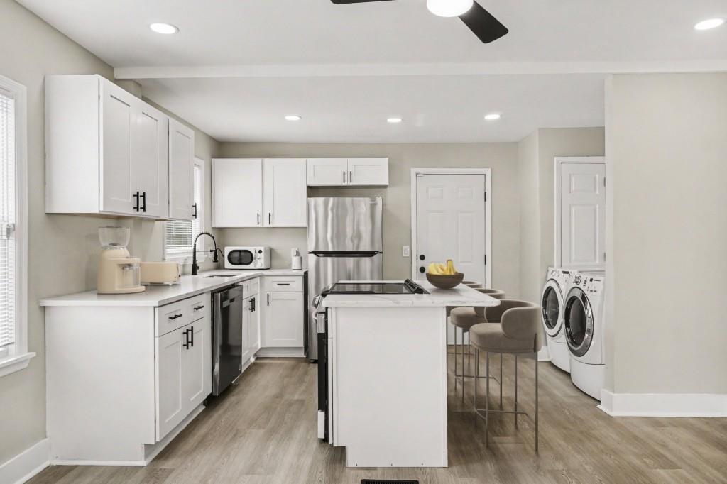 1515 Jonesboro Road Southeast Atlanta, GA 30315 - Photo 3 of 32 a kitchen with a stove a refrigerator and white cabinets with wooden floor