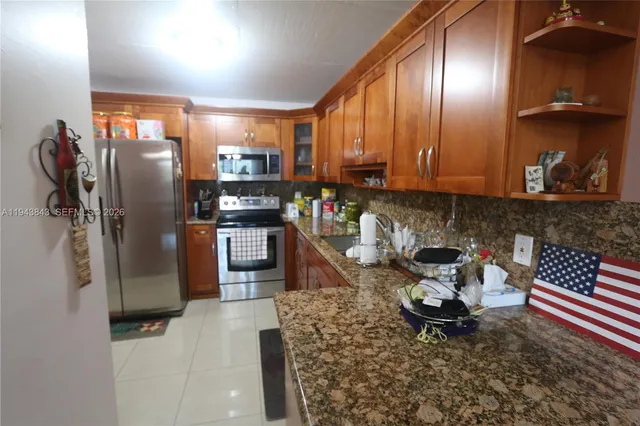 a kitchen with stainless steel appliances granite countertop a refrigerator a stove and a sink