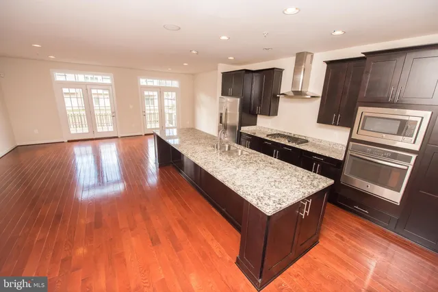 a kitchen with kitchen island granite countertop wooden floors and wide window