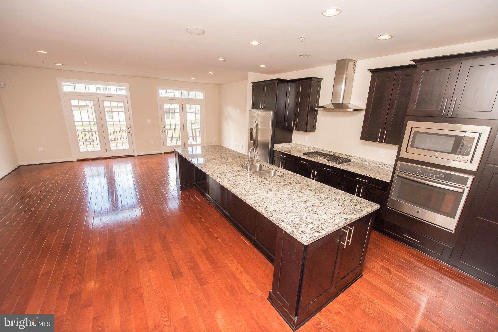 7444 Burnside Way Hanover, MD 21076 - Photo 6 of 46 a kitchen with kitchen island granite countertop wooden floors and wide window