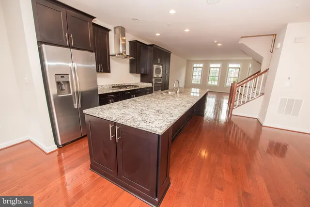 a kitchen with stainless steel appliances granite countertop a refrigerator a stove and a wooden floors