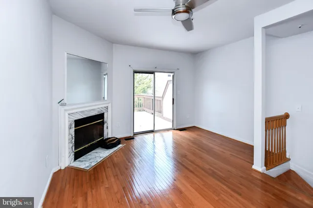 a view of an empty room with wooden floor fireplace and a window