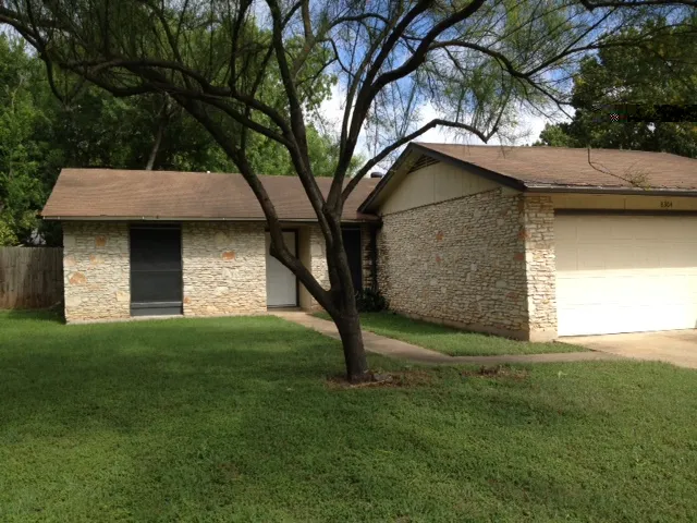 a view of a yard in front of a house with large tree