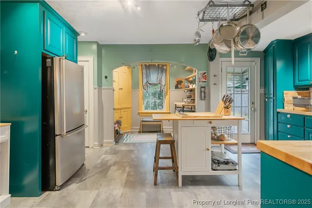 a kitchen with stainless steel appliances kitchen island granite countertop refrigerator and cabinets