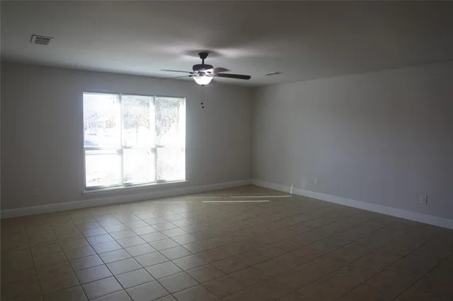 an empty room with windows and fan
