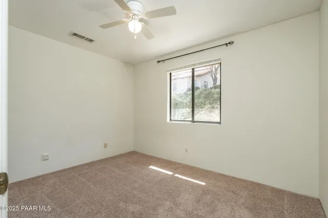 an empty room with a window and a fan