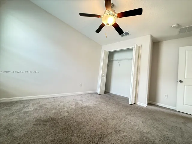 an empty room with closet and a chandelier fan