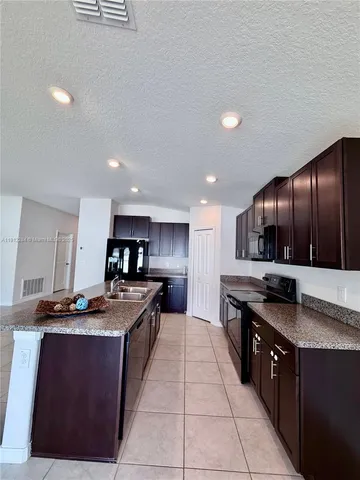 a kitchen with stainless steel appliances granite countertop a stove a sink a refrigerator and a wooden cabinets